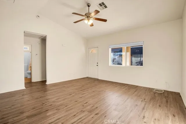 an empty room with wooden floor and a ceiling fan
