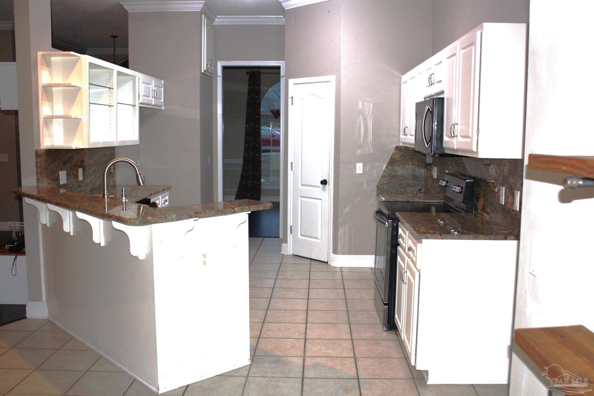 5708 Tamarack Drive Pace, FL 32571 - Photo 21 of 29 a kitchen with a sink a stove top oven and a refrigerator