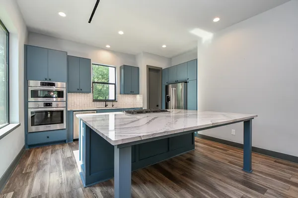 a kitchen with stainless steel appliances granite countertop a kitchen island hardwood floor sink stove dining table and chairs