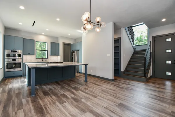 a kitchen with stainless steel appliances granite countertop a refrigerator a stove and a wooden floors