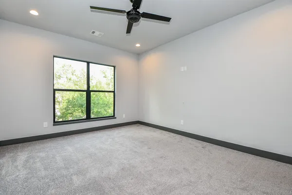 an empty room with windows and ceiling fan