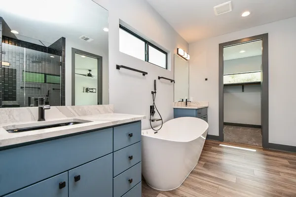 a bathroom with a double vanity sink a mirror and a bathtub