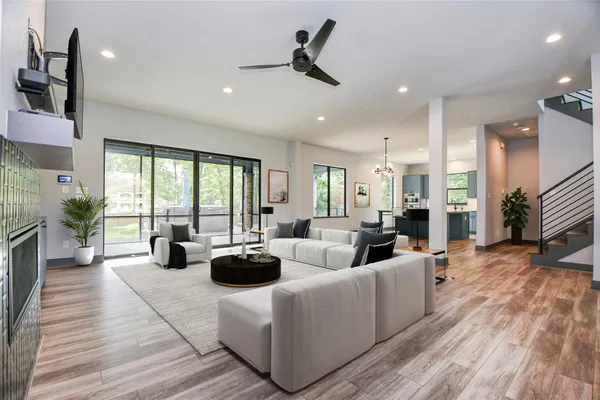 a living room with furniture large windows and wooden floor
