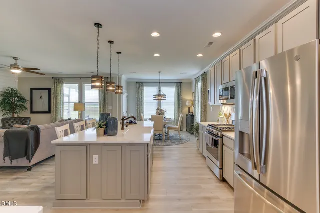 a kitchen with stainless steel appliances granite countertop a refrigerator a oven a sink and white cabinets