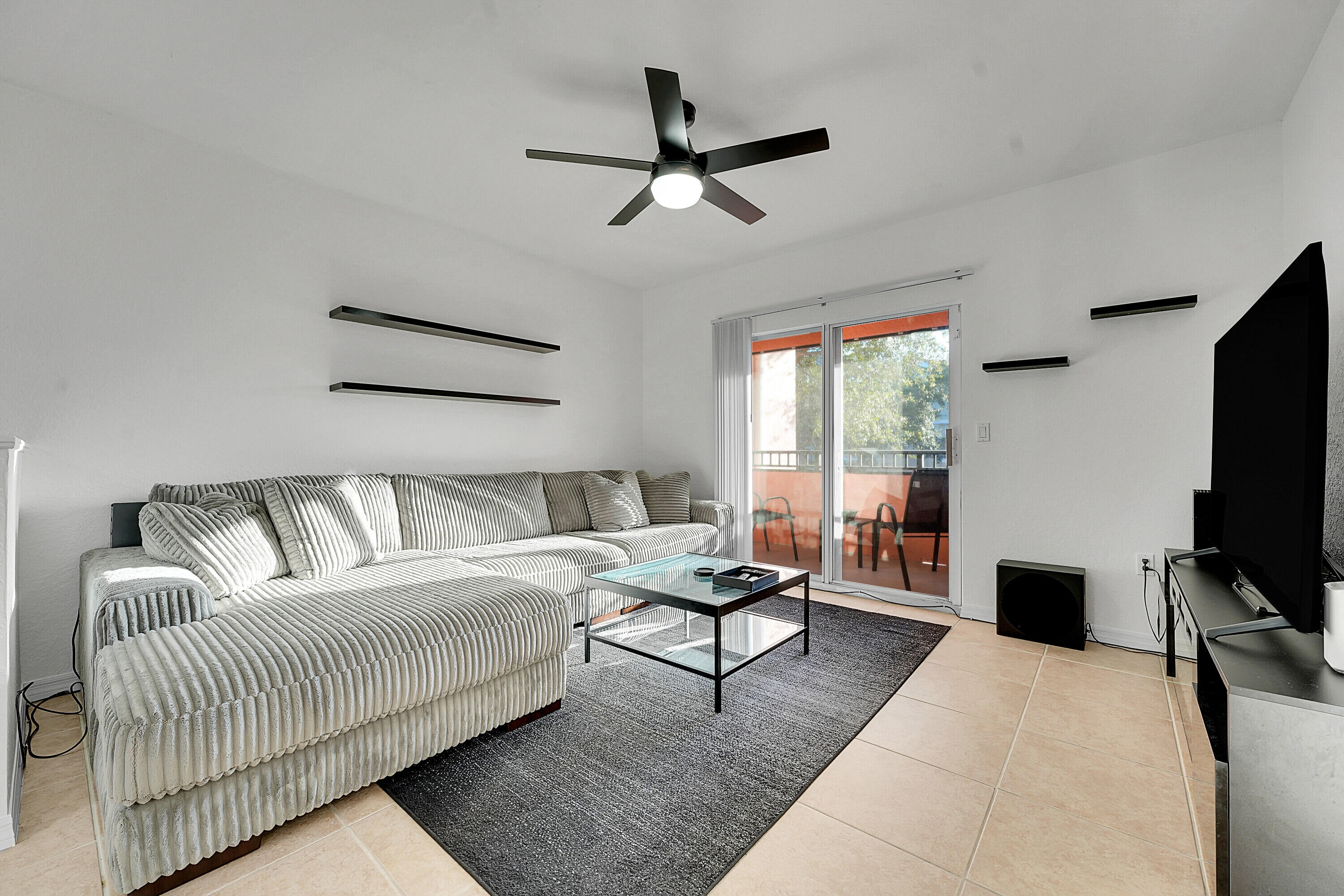 162 Southwest Peacock Boulevard, Unit 32206 Port St. Lucie, FL 34986 - Photo 5 of 24 a living room with furniture and a flat screen tv