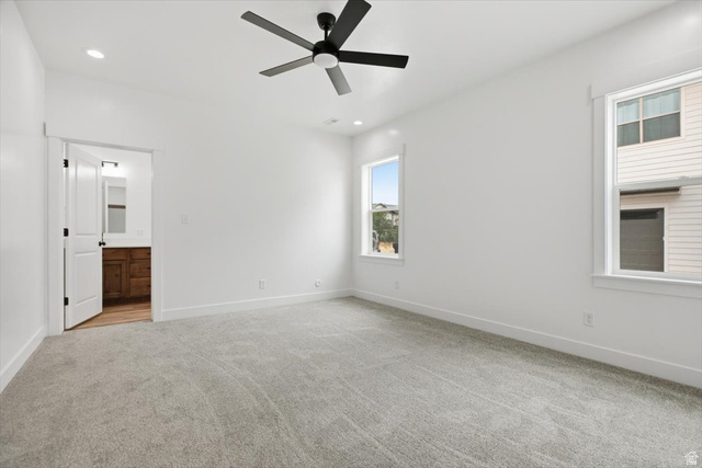 164 North 400 East Preston, ID 83263 - Photo 9 of 21 Carpeted room featuring a ceiling fan with integrated lighting, two windows, and a doorway leading to a bathroom with a wood-finish vanity