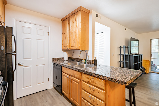 1221 Waterside Cove, Unit 11 Midvale, UT 84047 - Photo 7 of 23 Kitchen featuring granite countertops, wood-finish cabinetry, a stainless steel sink, and a black dishwasher