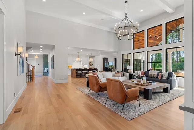 a living room with furniture a chandelier and wooden floor