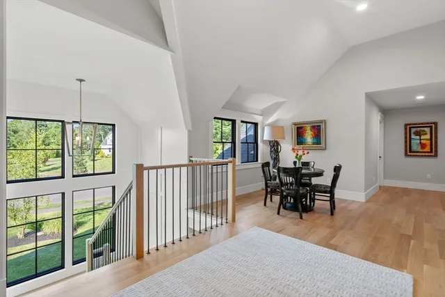 a view of a dining room and livingroom with furniture wooden floor a rug a fireplace and a window