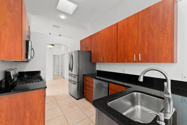 a kitchen with granite countertop a sink a stove and refrigerator