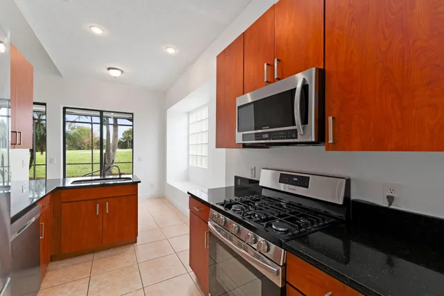 a kitchen with stainless steel appliances granite countertop a stove a sink and a microwave