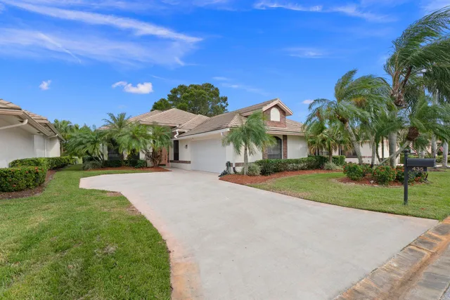 a front view of a house with a yard and potted plants