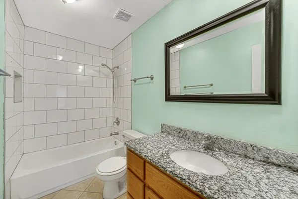 a bathroom with a granite countertop toilet sink and mirror