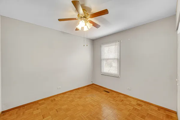 an empty room with a chandelier fan and windows