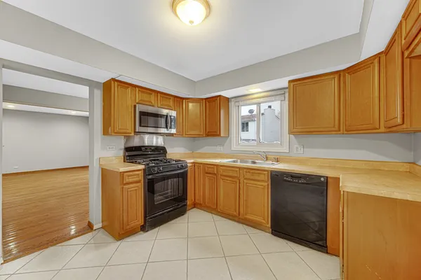 a kitchen with stainless steel appliances granite countertop a stove a sink dishwasher and a microwave oven with white cabinets