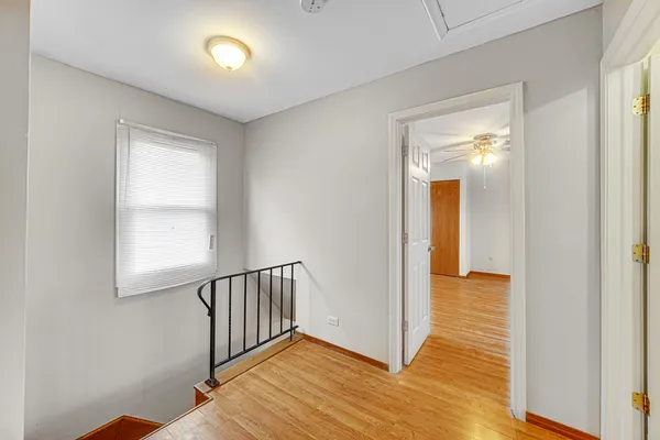 a view of a hallway with wooden floor and a bathroom