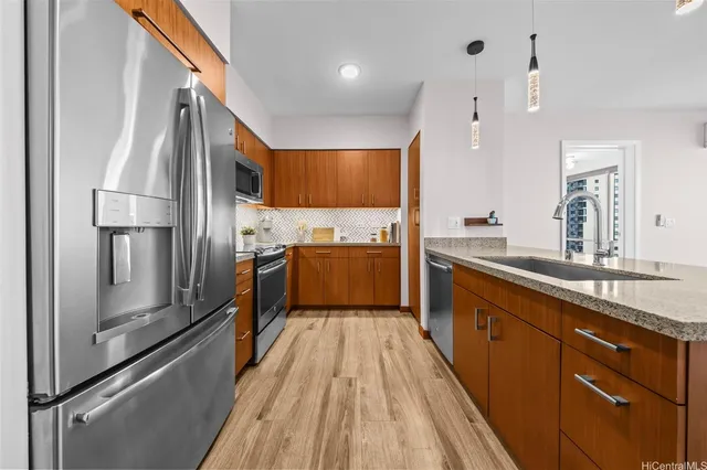 a kitchen with kitchen island granite countertop a refrigerator a sink a stove and oven