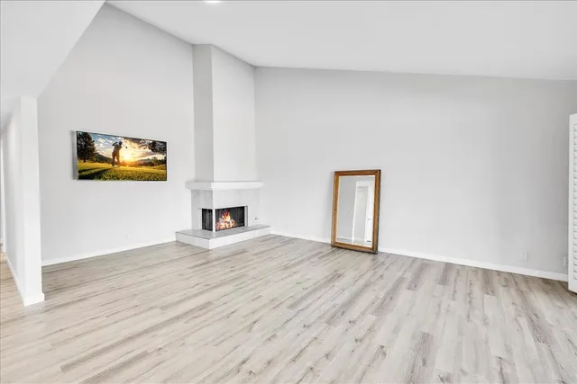 a view of empty room with wooden floor and fireplace