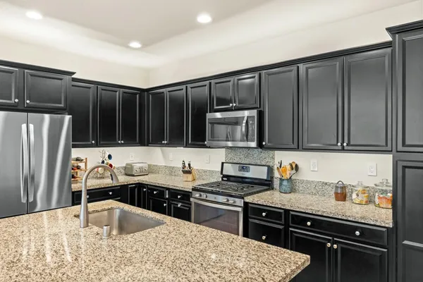 a kitchen with kitchen island granite countertop a sink stainless steel appliances and cabinets