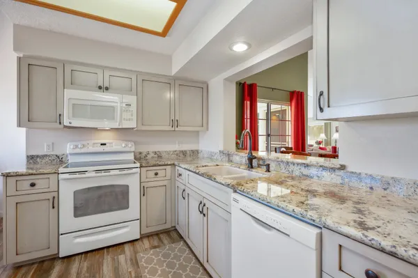 a kitchen with granite countertop white cabinets and white stainless steel appliances