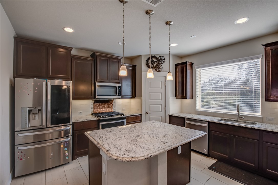 9707 McKnight Loop Austin, TX 78717 - Photo 7 of 17 a kitchen with kitchen island a counter space a refrigerator and a sink