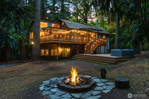 a view of a fountain in the yard next to a brick house with large trees