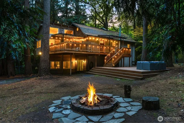 a view of a fountain in the yard next to a brick house with large trees