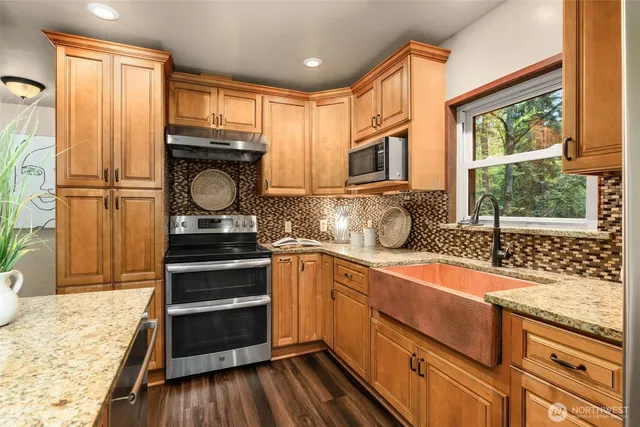 a kitchen with granite countertop stainless steel appliances a stove sink and cabinets