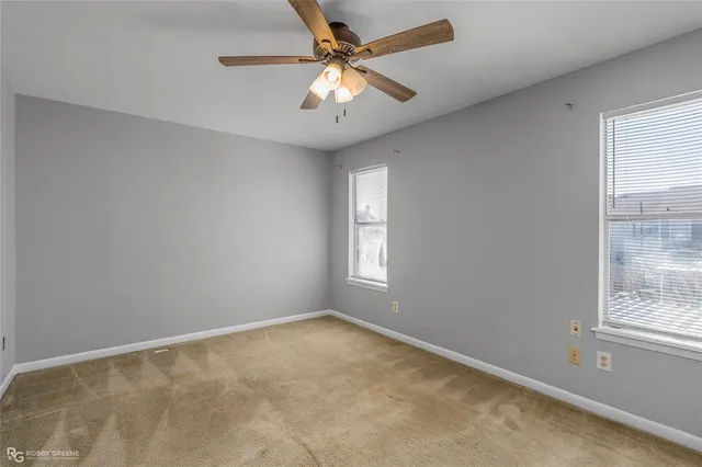 an empty room with a window and a fan