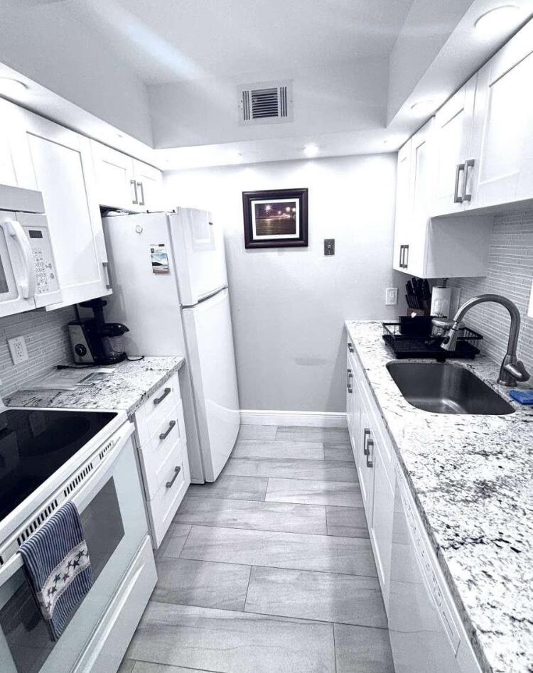 111 Briny Avenue, Unit 703 Pompano Beach, FL 33062 - Photo 2 of 19 a kitchen with stainless steel appliances granite countertop a sink stove and refrigerator