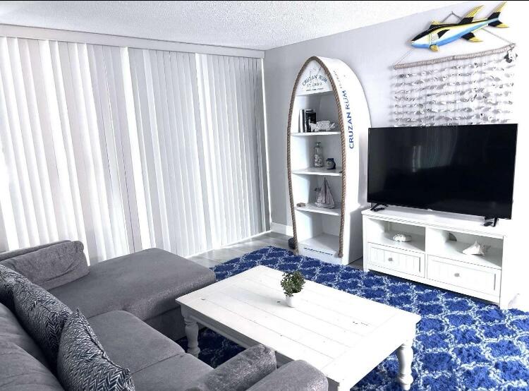 111 Briny Avenue, Unit 703 Pompano Beach, FL 33062 - Photo 3 of 19 a living room with a flat screen tv and a rug