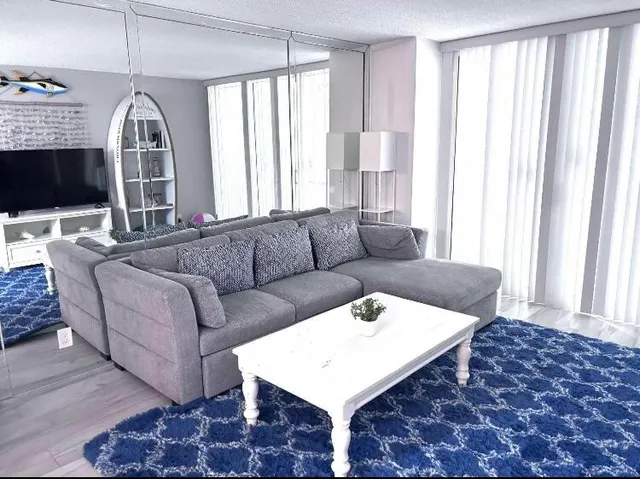 a living room with furniture a flat screen tv and a large window