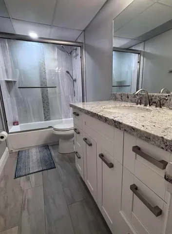 a bathroom with a granite countertop sink toilet and shower