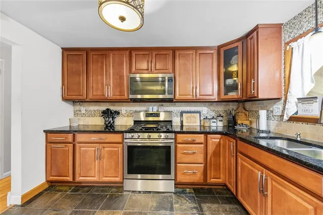 a kitchen with stainless steel appliances granite countertop a stove a sink and a microwave