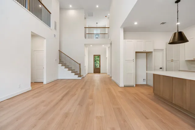 a view of an empty room with kitchen and window