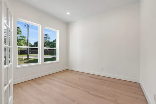 an empty room with wooden floor and windows