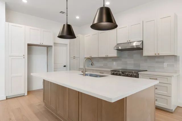 a kitchen with stainless steel appliances a stove a sink a refrigerator a counter space and cabinets