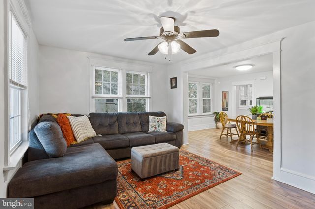 a living room with furniture and a dining table with wooden floor