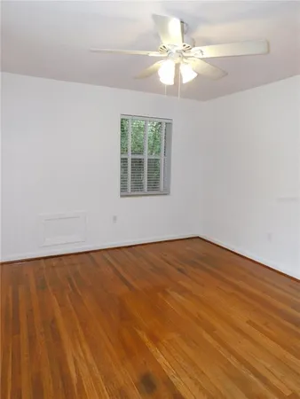 an empty room with wooden floor fan and windows