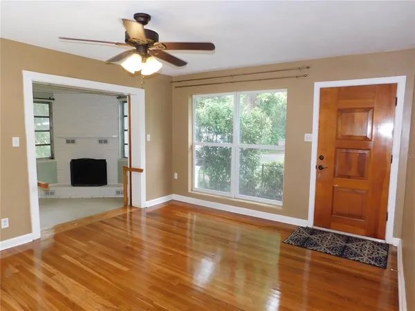 a view of empty room with wooden floor and fan