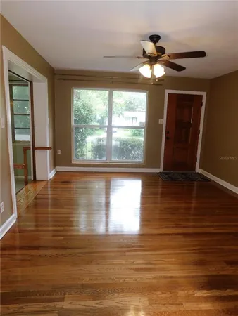 a view of empty room with wooden floor and fan