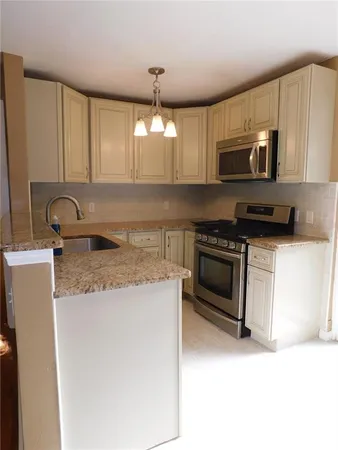 a kitchen with stainless steel appliances granite countertop a sink a stove a microwave and cabinets