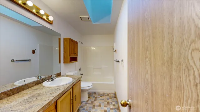 a bathroom with a granite countertop sink a toilet and shower