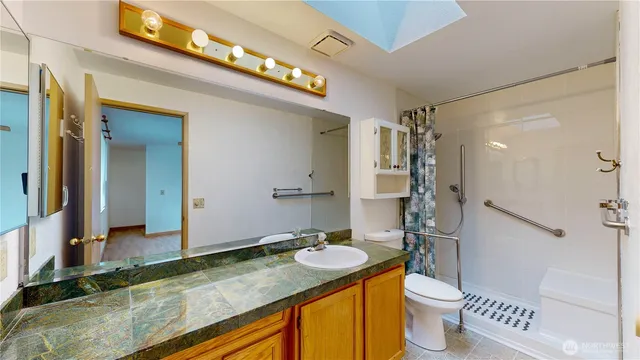 a bathroom with a granite countertop sink toilet and shower