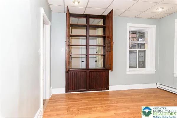 a view of an empty room with wooden floor and a window