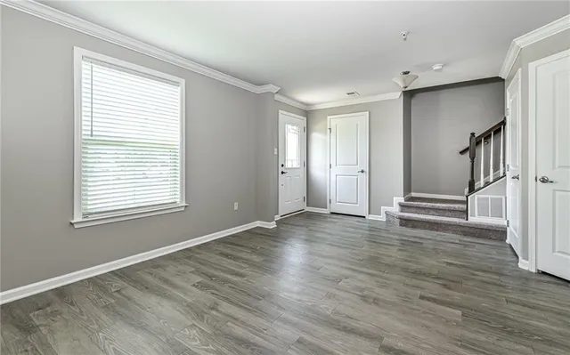 a view of an empty room with wooden floor and a window