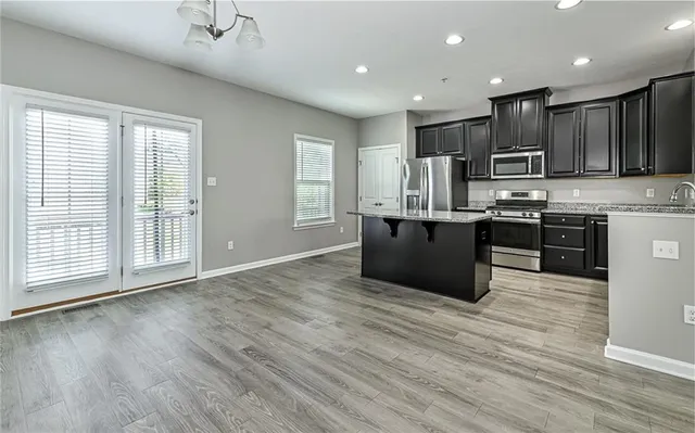 a kitchen with stainless steel appliances granite countertop a stove top oven a sink dishwasher a refrigerator and a oven with wooden floor