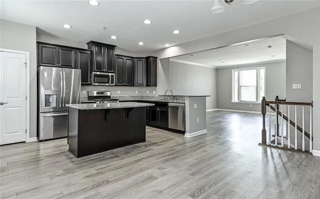 a kitchen with stainless steel appliances granite countertop a refrigerator a stove top oven and cabinets