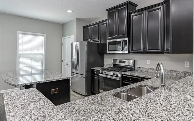 a kitchen with stainless steel appliances granite countertop a stove a sink and a refrigerator