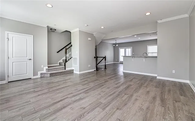 a view of empty room with wooden floor and kitchen